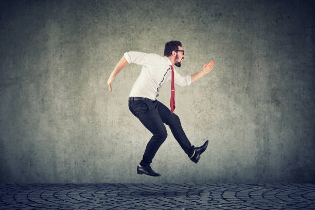 istock Young businessman running jumping against wall background 1182491658