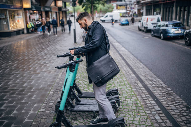 hombre alquilando patinete scooter - bikeshare fotografías e imágenes de stock