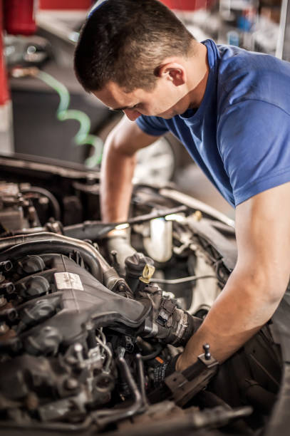 istock Car mechanic repairer service technician checks and repairs auto engine 1182497357
