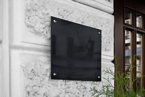 Blank black glass signplate on textured wall mockup. Empty lawyer square nameplate mock up. Clear glassy banner for shop or office entry mokcup template.