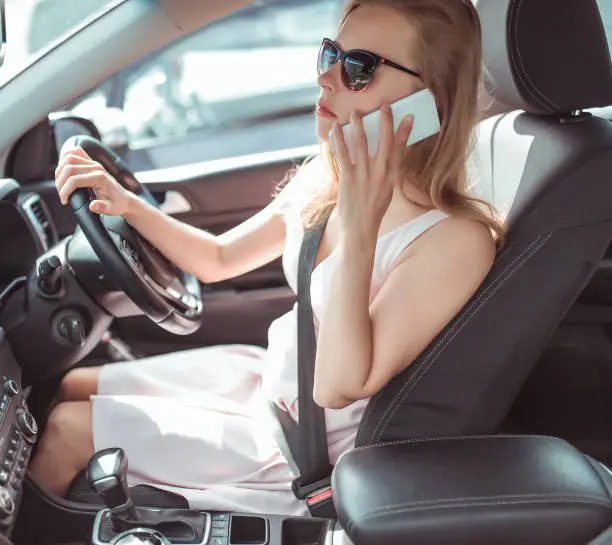 Girl driving car in cabin. Right-hand drive, left-hand drive. Calls phone, stands in traffic, parking waiting for passenger, specify meeting place. Listens to message in application online call