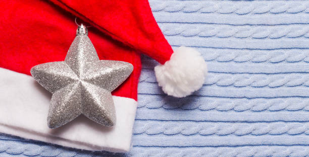 istock Red Santa hat with silver star on blue background with copy space 1182503145