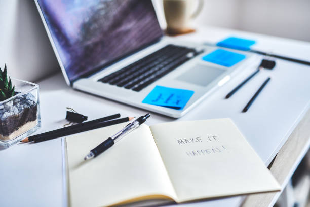Shot of a notebook with “make it happen” written in it at a work desk
