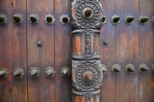 Ancient traditional wooden carved door with ornaments and bronze spike in Stone Town, Zanzibar, Tanzania, East Africa. Close up. Selective focus