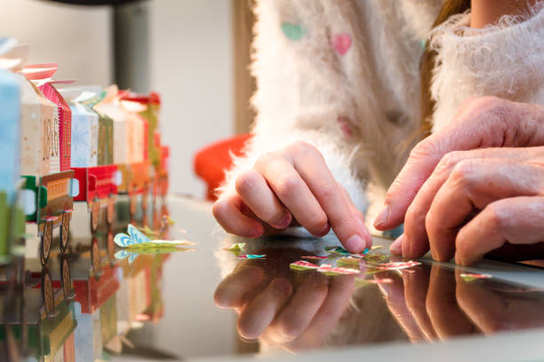 close up hands of girl with grandmother opening advent calendar - advent calendar advent christmas childhood fotografías e imágenes de stock