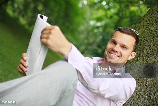 Sonriente Joven Lectura Y Foto de stock y más banco de imágenes de Leer - Leer, Revista - Publicación, Aire libre