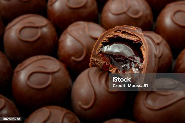 Sweet Confectionery And Candy Indulgence Concept Theme With Close Up On A Bitten Cherry Filled Chocolate Praline On Top Of Many Other Delicious Pralines With Copy Space Stock Photo - Download Image Now