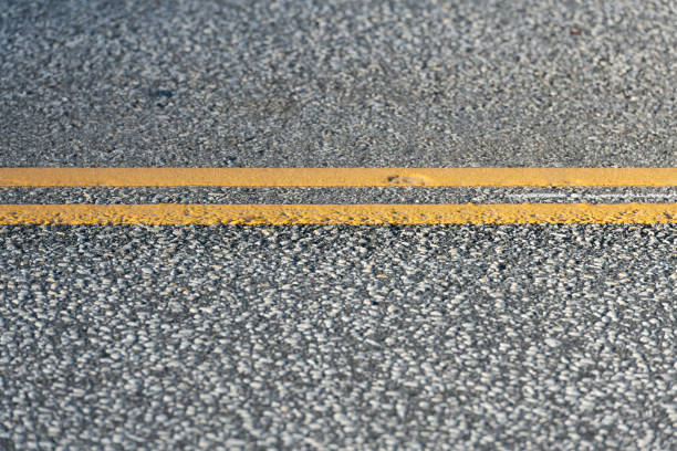 Street or road asphalt with double yellow dividing lines. Shallow depth of field.