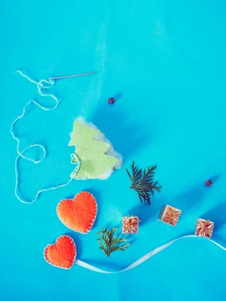 Sewing a felt Christmas tree for seasonal winter holidays, hearts, decor on a blue background