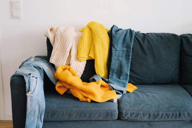 istock Couch covered in messy clothing 1182511149