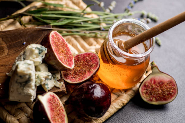 istock honey, figs and cheese on a wicker plate. Black background 1182512456