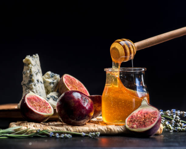 honey, figs and cheese on a wicker plate. Black background