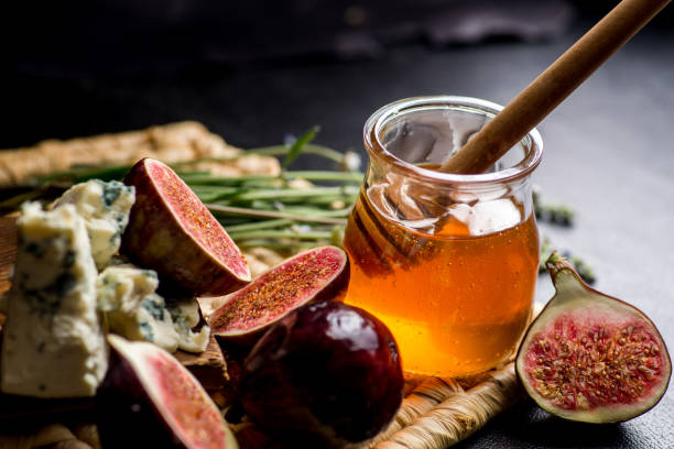 istock honey, figs and cheese on a wicker plate. Black background 1182512484