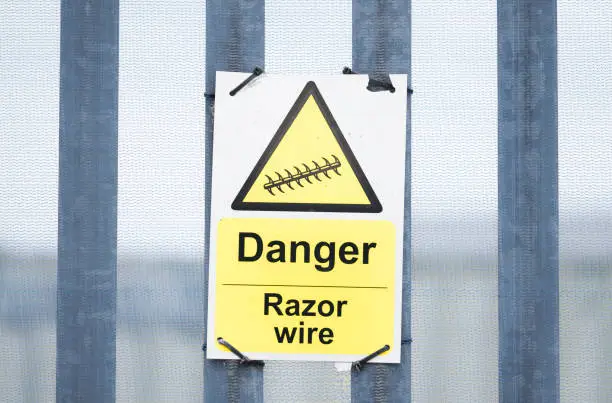 Photo of Razor wire danger sign on security fence