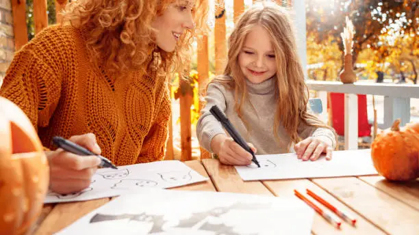 Photo of Mother and little daughter drawing spooky ghost for halloween