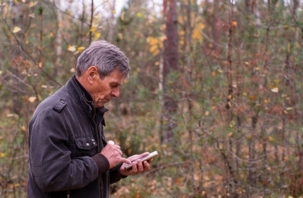 istock Senior man checking the direction in a forest on the map with a mobile application installed on a smartphone. 1182520434