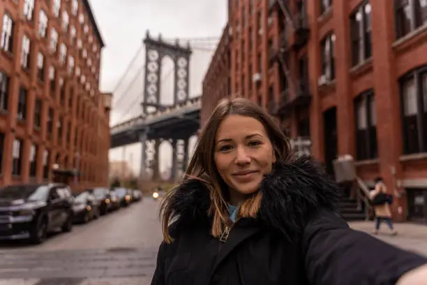 Photo of woman taking a selfie near the manhattan bridge in new york