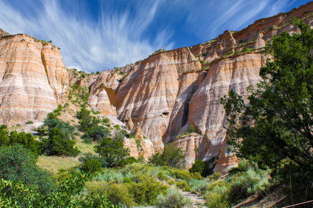 Tent rocks mountain Tent rocks National monument in New Mexico, scene of multi layered mountain sides with green bushes and trees in the forefront and a wispy cloudscape in the background santa fe new mexico mountains stock pictures, royalty-free photos & images