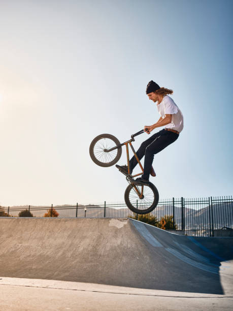 Bicycle Rider in a Skate Park A young man doing stunts and jumping a bicycle in a skate park. bicycle stunts stock pictures, royalty-free photos & images