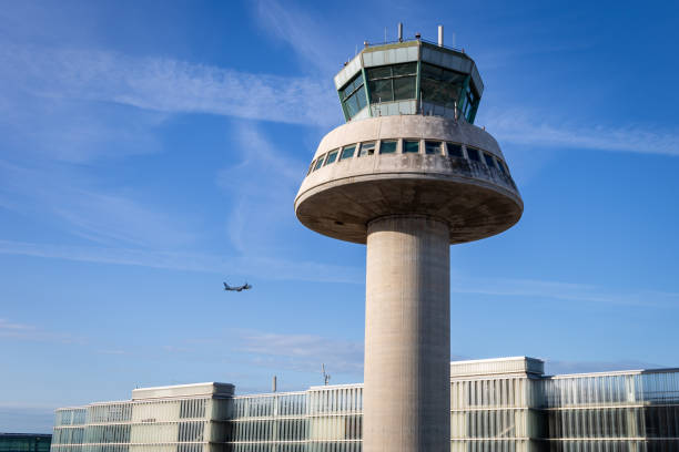 a plane flies next to the air traffic control tower at josep tarradellas barcelona el prat airport, spain - air traffic control tower fotografías e imágenes de stock