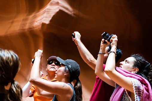 Page, USA - August 10, 2019: Tour group of young people inside Upper Antelope slot canyon in Arizona taking pictures with camera of sandstone formations