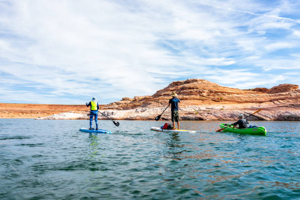 Sunny day at Lake Powell with group of people doing stand up paddle boarding boats Page, USA - August 9, 2019: Sunny day at Lake Powell with group of people doing stand up paddle boarding boats and view of canyons water lower antelope canyon stock pictures, royalty-free photos & images