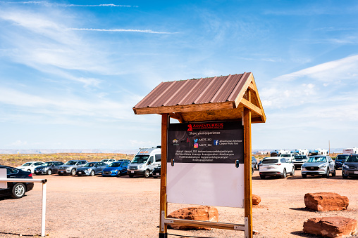 Page, USA - August 10, 2019: Sign entrance to Navajo tribal Adventurous tours at Upper Antelope slot canyon in Arizona and parking lot with cars