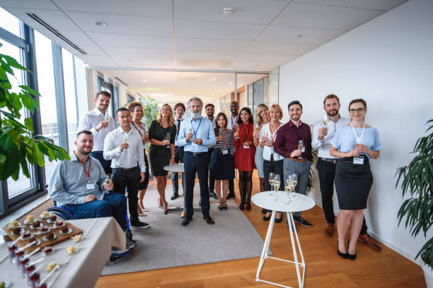 Proud CEO Posing with Staff of New Business Group portrait of bearded CEO in mid 50s standing with staff of new business and holding glass of sparkling wine for celebratory toast. organized group photos stock pictures, royalty-free photos & images