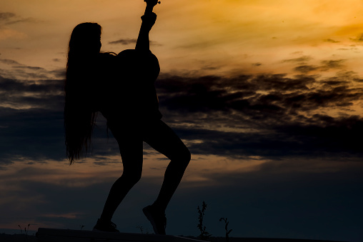 Albion, Mauritius - April 02, 2023: Silhouette of young woman at the beach in the West of Mauritius during sunset.