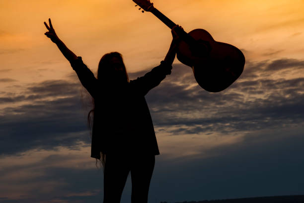 istock Silhouette woman playing guitar in sunset 1182527682
