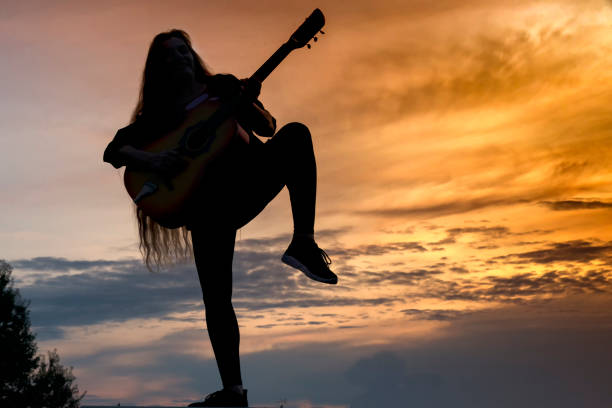 istock Silhouette woman playing guitar in sunset 1182527706