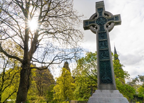 Sun shines on Celtic Cross in cemetery.