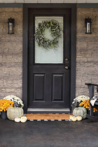 Front Porch Decorated for Thanksgiving Day Front porch decorated for Thanksgiving Day with homemade wreath hanging on door. Heirloom gourds,  white pumpkins, and mums giving an inviting atmosphere. front porch stock pictures, royalty-free photos & images