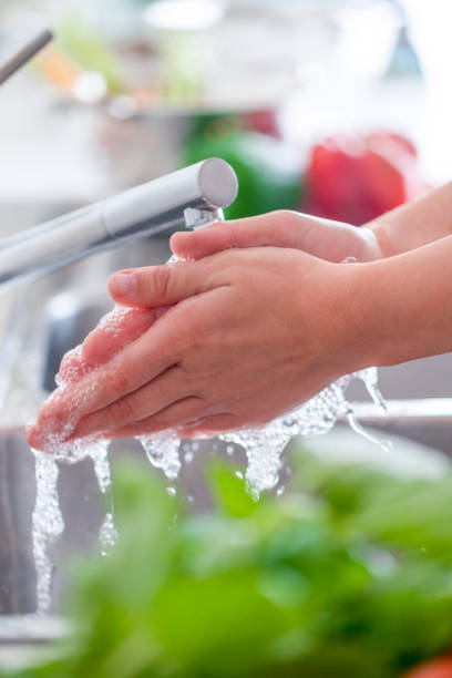 istock Woman washing her hands at the kitchen sink. 1182531491