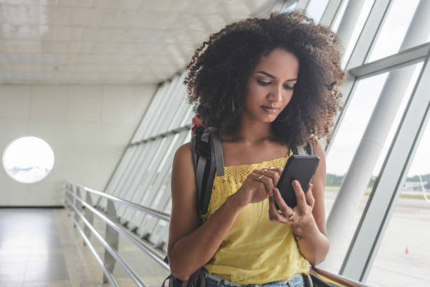 istock Young woman with backpack checking her boarding schedule at the airport 1182533896