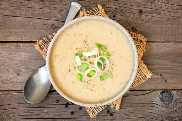 Potato and leek soup, top view table scene on a rustic wood background