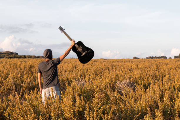 istock Man holding a guitar in raised arm 1182534980
