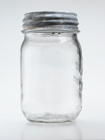 Glass jar full of peanut butter with black closed lid, white blank label