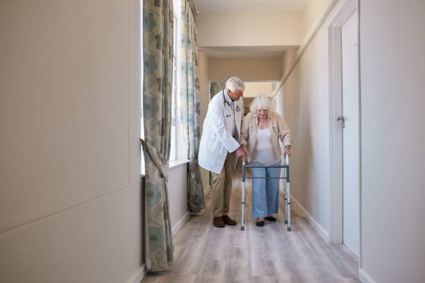 istock Doctor helping his elderly patient use her walking frame 1182538044