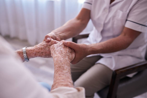 istock Nurse holding hands with an elderly female patient 1182538763