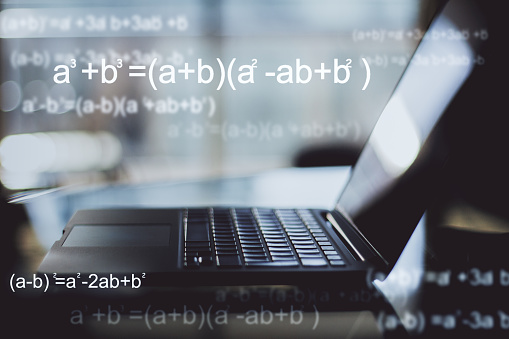 Programming and computing concept. Close up of blurry laptop with mathematical formulas. Double exposure