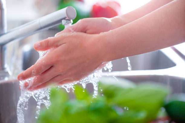 istock Woman washing her hands at the kitchen sink. 1182541282