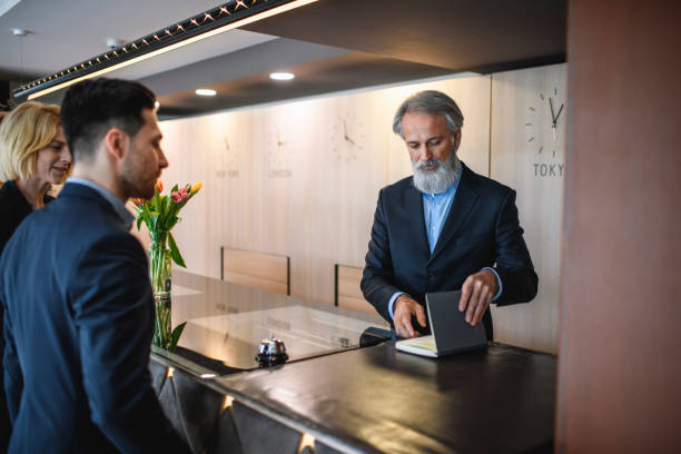 istock Senior Hotel Receptionist Assisting Guests Checking Out 1182549211