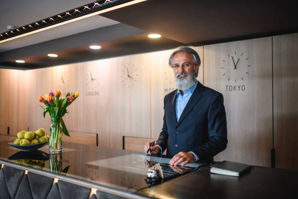 istock Smiling Mature Male Hotel Receptionist at Front Desk 1182549216