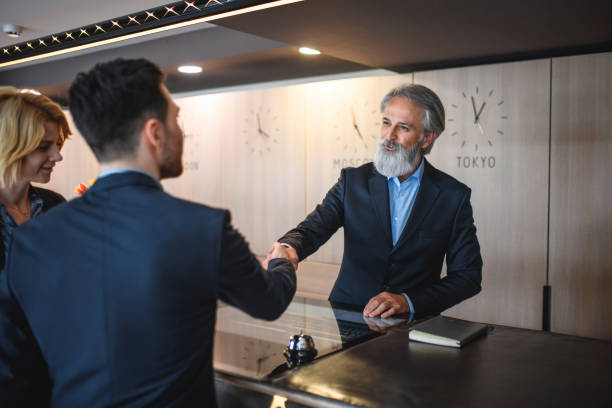 istock Cordial Mature Hotel Receptionist Shaking Hands with Guest 1182549219
