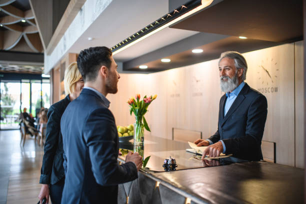 istock Senior Hotel Receptionist Assisting Young Business Guests 1182549221