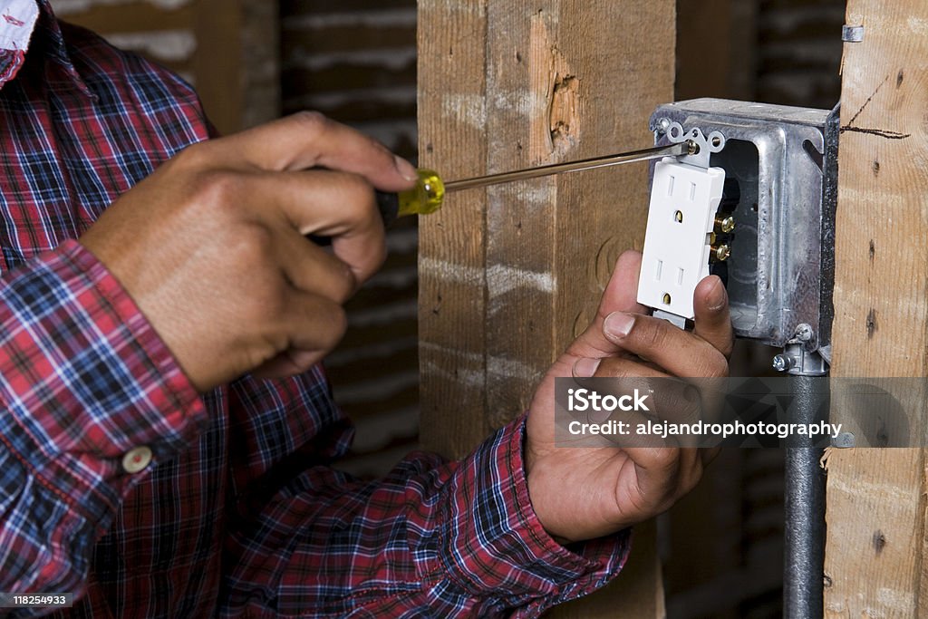 Mãos prender em uma tomada elétrica - Foto de stock de Setor de construção royalty-free