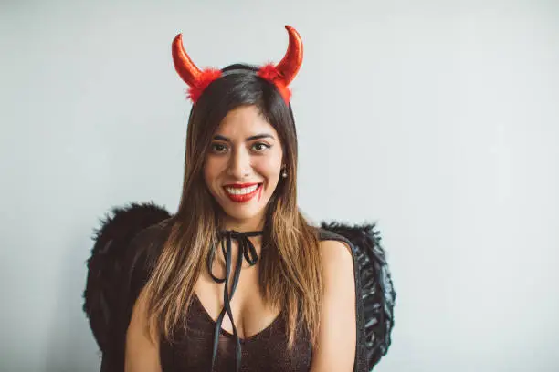 Young woman celebrating Halloween dressed-up in devil costume with horns