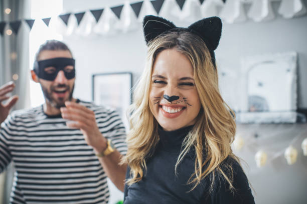 Halloween couple on party Young couple at home party celebrating Halloween in costume of thief and cat-woman carnival mask women party stock pictures, royalty-free photos & images