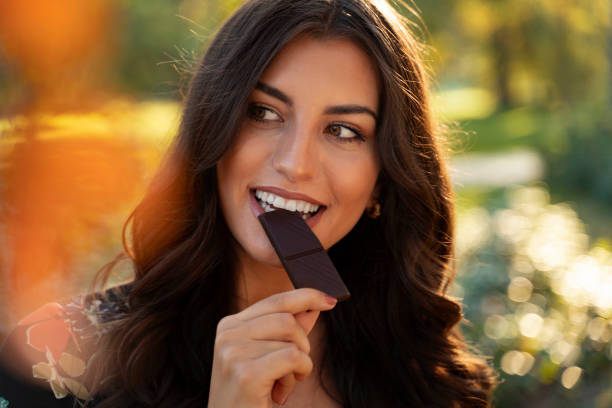 istock gorgeous elegant young woman eating dark chocolate 1182555408